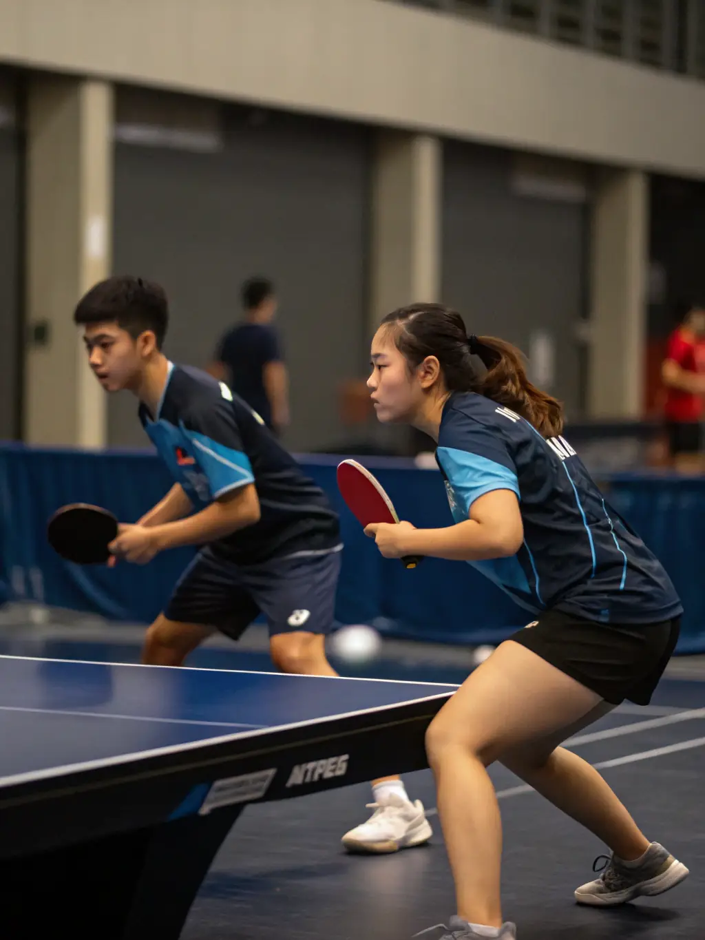 Action shot of a local table tennis league match at ETT, capturing the intensity and excitement of the competition, with spectators cheering in the background.